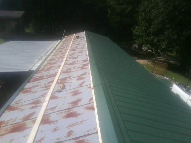 Old rusted panels beside newly installed green metal roofing — Wind Damage Roof Repair by Roofing Brothers in Peabody