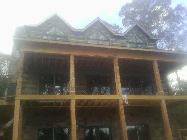 Dormers and porch framing on a large log home under construction — Roof Coating work by our crew in Peabody