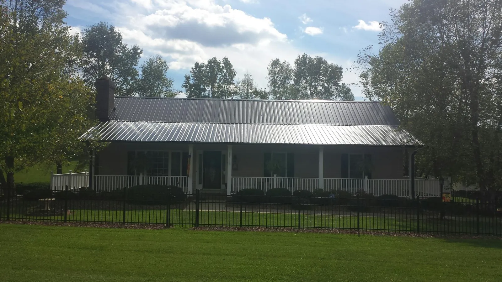 Gray metal roof on a brick ranch with a full width front porch — Gutter Guard Installation work by our crew in Peabody