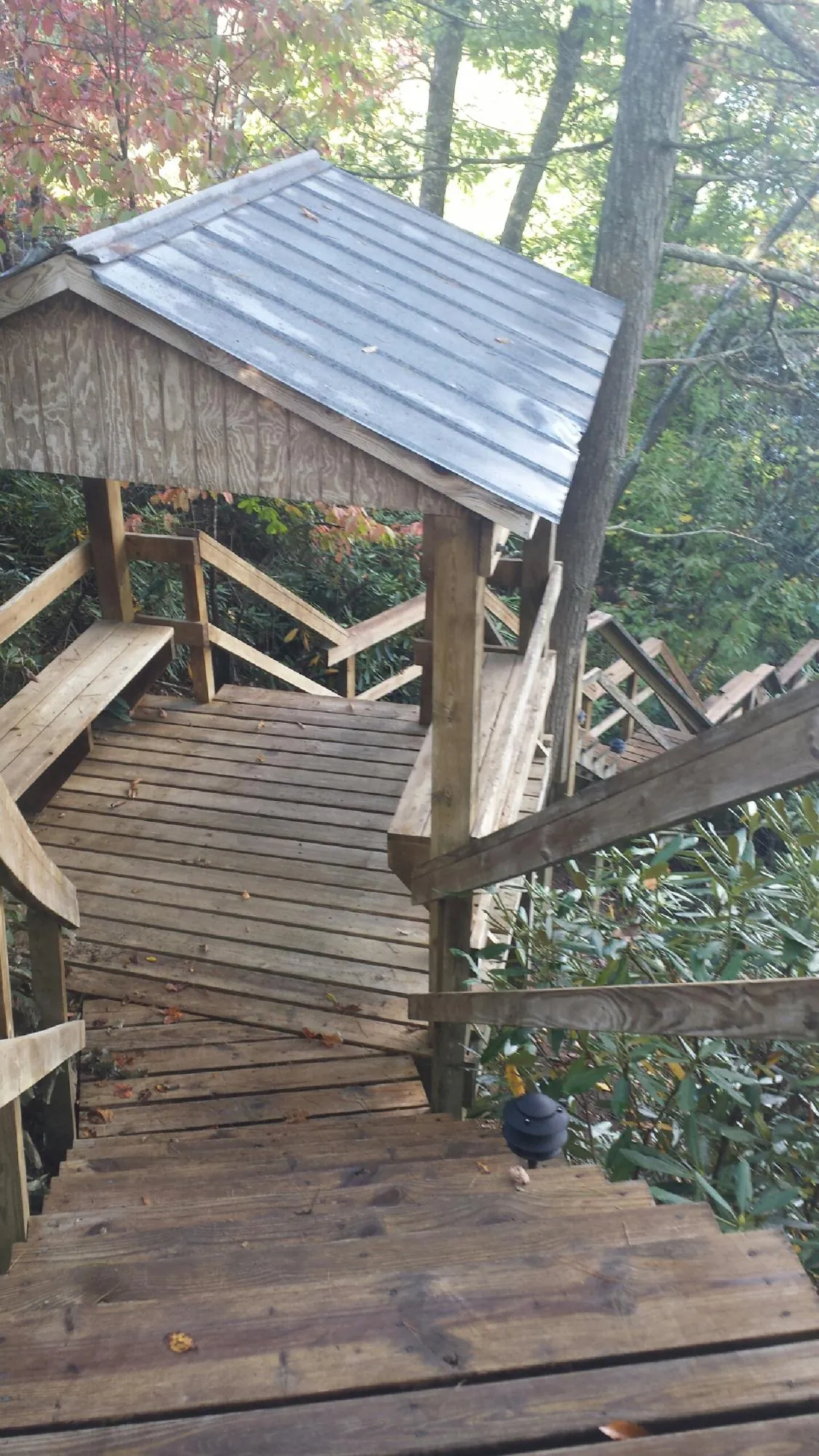 Metal roofed shelter over wooden steps on a wooded walkway — Skylight Repair & Installation work by our crew in Peabody