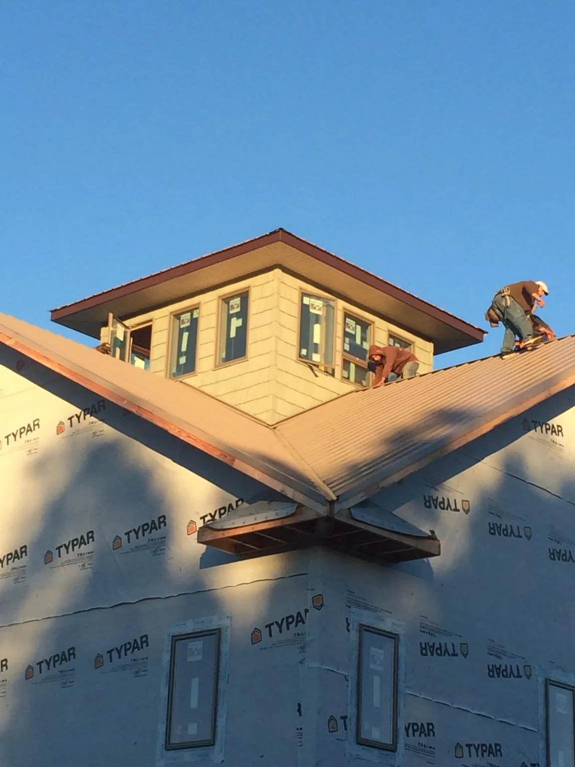 Roofers working around a rooftop cupola on a new metal roof at sunset — Roof Waterproofing in Peabody by Roofing Brothers